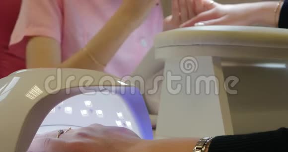 关闭一个紫外线LED灯与一个女性手内固定凝胶指甲油视频的预览图