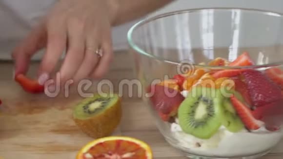鲜果多汁水果甜水果沙拉一家人穿着白色t恤衫在厨房里煮美味的食物视频的预览图