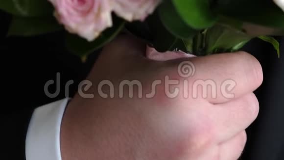一个穿西装的男人手里拿着一束五颜六色的玫瑰特写镜头送给心爱的人美丽的鲜花礼物视频的预览图