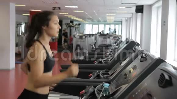 在健身房里一个苗条的女人沿着跑步机跑步视频的预览图