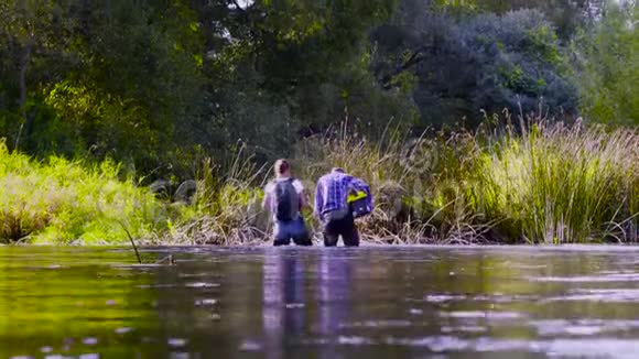 两位科学家穿着高橡皮靴在森林河的水中行走视频的预览图