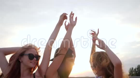 在夏日日落的背景下与朋友结伴在沙滩上欢乐的三位女性在日落时跳舞视频的预览图