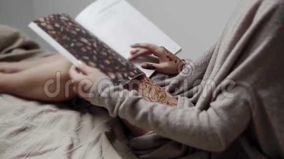 年轻女子晚上坐在床上看书拍摄细节视频的预览图