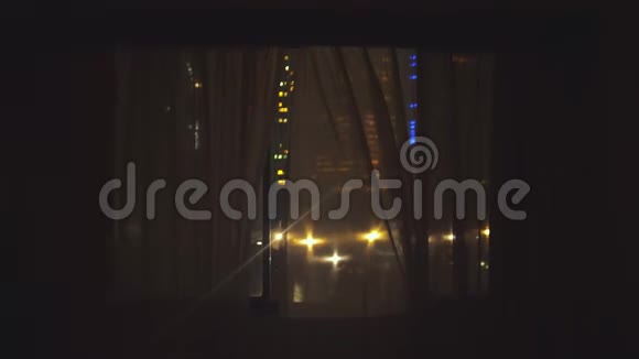 年轻人跑到窗户边打开窗帘欣赏夜晚从窗户上看到的风景4k3840x2160视频的预览图