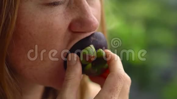 一个红头发女人吃新鲜多汁的芒果特写镜头视频的预览图