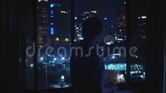 年轻人晚上从窗户欣赏家中的风景喝茶3840x2160视频的预览图