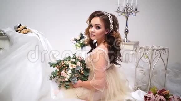 美丽的新娘被婚纱包围围绕着花束和装饰直接看着摄像机大视频的预览图