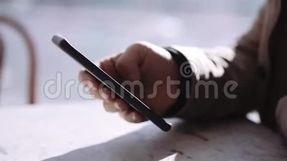 咖啡馆里的男人手里拿着智能手机在滚动视频的预览图