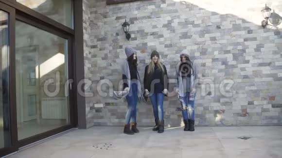 三个穿着帽子和毛衣的漂亮女孩在院子里玩得开心视频的预览图