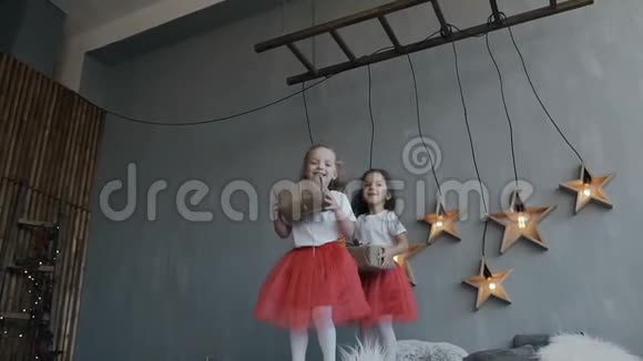 双胞胎的两个小妹妹在父母的床上积极地玩着穿着相同红色衣服的儿童视频的预览图