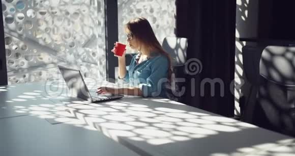 女人浏览笔记本电脑和喝咖啡视频的预览图