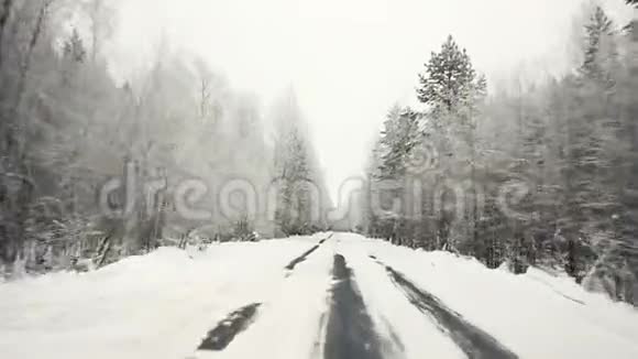 驱车穿越冬林雪道初观在stealicam的窗户外的摄像头冬季景观视频的预览图