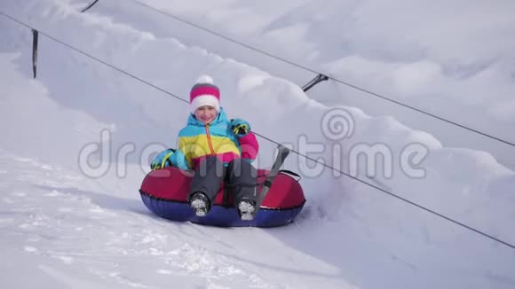 年轻女孩骑在一座小山上的充气雪管上视频的预览图