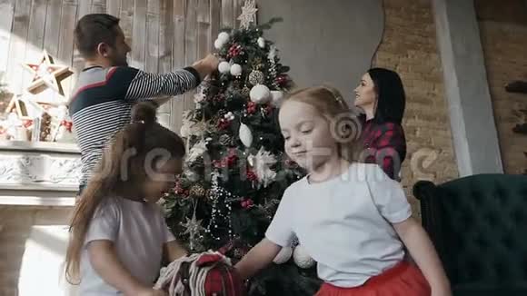 特写镜头快乐的年轻父母装饰圣诞树他们的双胞胎女儿骑玩具马新年快乐视频的预览图
