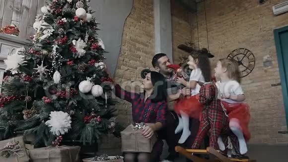 幸福的家庭一起装饰圣诞树父母和两个女儿在圣诞礼物上玩耍视频的预览图