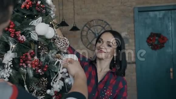 特写镜头一个漂亮的年轻女人和她的丈夫一起兴高采烈地装饰一棵圣诞树一个幸福的家庭圣诞节视频的预览图