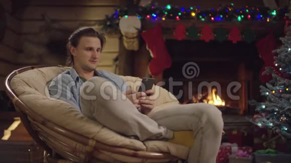 在圣诞夜使用智能手机的长发青年视频的预览图