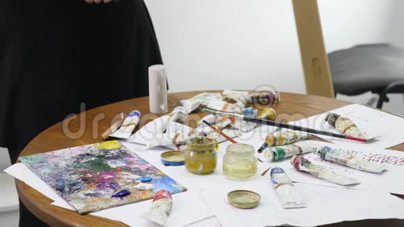画家在画廊的书桌涂了五彩的油画将颜料和艺术家木槌上的空管混合视频的预览图