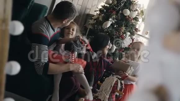 一个幸福的家庭展示在一个房间的镜子里一个壁炉旁边的圣诞树年轻的家庭很高兴视频的预览图