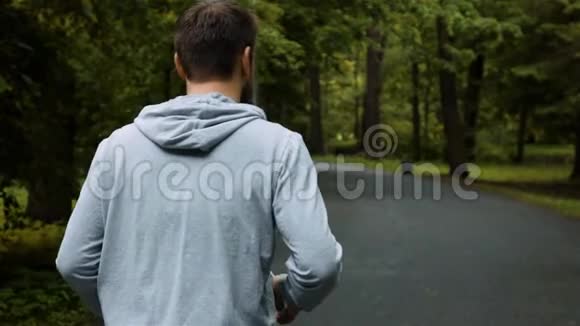 秋色自然公园外面年轻英俊的跑步者带着电话视频的预览图