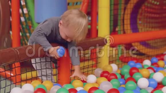 小金发男孩试图用球从干池里接住球他的母亲把他放在干池里视频的预览图