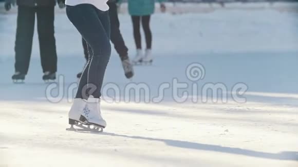 一个年轻女孩的腿熟练地在户外公共冰场滑冰慢动作视频的预览图