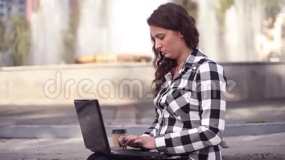 年轻美丽快乐的商务女性在喷泉附近的公园工作笔记本电脑视频的预览图