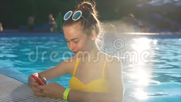 在泳池里的一个成年女孩把照片放在手机上的社交网络上视频的预览图