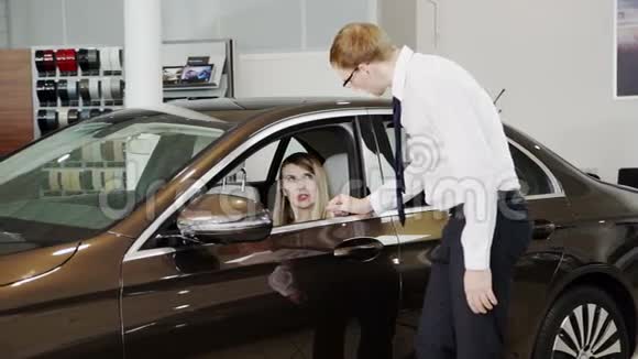 销售人员在展厅内向女士展示高级轿车视频的预览图
