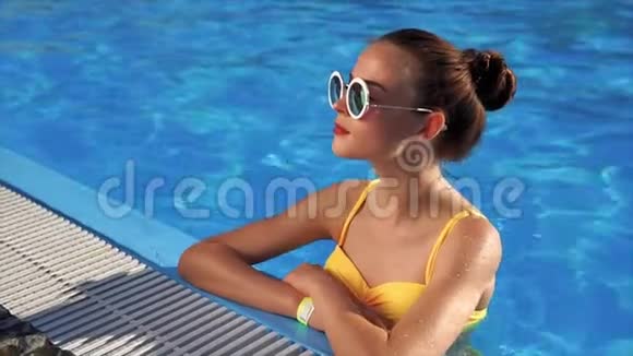 泳池里穿着泳衣的年轻美女摘下墨镜视频的预览图