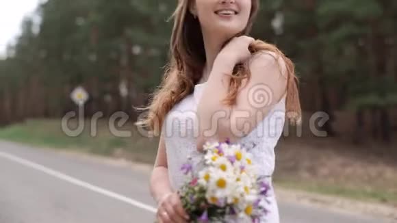 快乐的女孩穿着白色连衣裙带着一束雏菊微笑黑发女人在笑视频的预览图