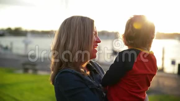 可爱时尚的年轻母亲和她的儿子享受美好的晴天儿子坐在母亲的手上视频的预览图