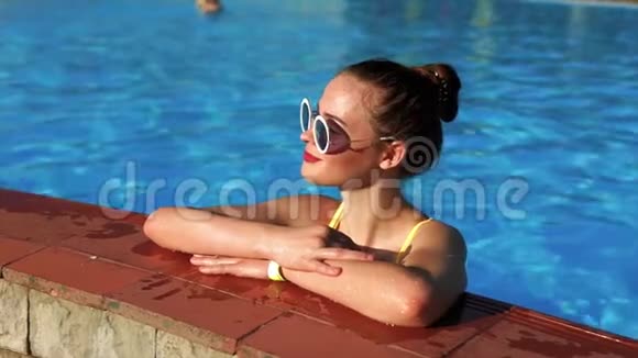 一个夏天在甲板椅上晒日光浴后成年女孩正在游泳池里降温视频的预览图