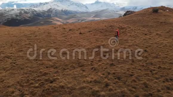 空中景色女孩旅行者带着相机在她的脖子上带着黄色的草走在斜坡上背景是视频的预览图