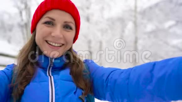 喀尔巴阡山年轻开朗的女人拿着相机在白雪覆盖的山景中拍摄自己视频的预览图