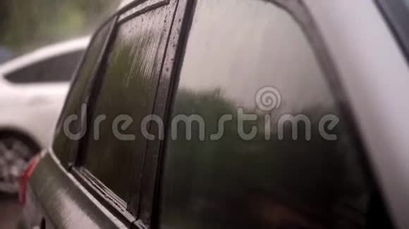 从外面看有大雨阵雨水滴落在空黑车的彩色窗户上视频的预览图