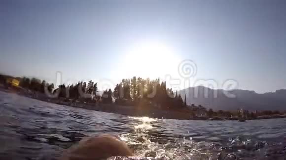 雄脚在海上水上游泳观点年轻人躺在水上摇腿慢动作关闭视频的预览图