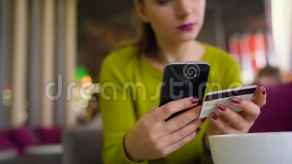 在咖啡馆里使用智能手机和信用卡在线支付的女人视频的预览图