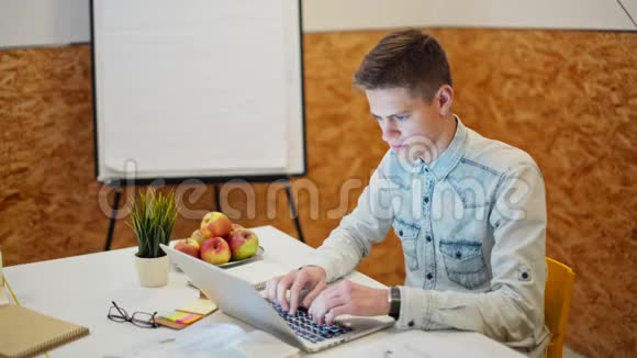 年轻的帅哥在舒适的办公室里做笔记本电脑视频的预览图
