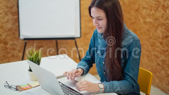 年轻漂亮的女士正在一间舒适的办公室里使用笔记本电脑视频的预览图