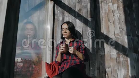 一对年轻漂亮的夫妇站在一个冬天寒冷的日子里靠近一扇大窗户喝着热腾腾的早晨咖啡快乐视频的预览图