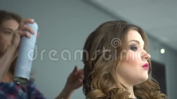 美发美容院美发师用发胶固定美女顾客发型视频的预览图