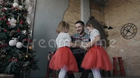 快乐的父亲在平安夜送给他的两个女儿礼物带礼物的快乐儿童视频的预览图