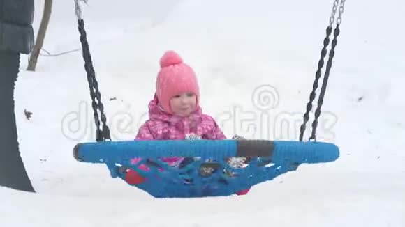 冬天可爱的小女孩在操场上荡秋千视频的预览图