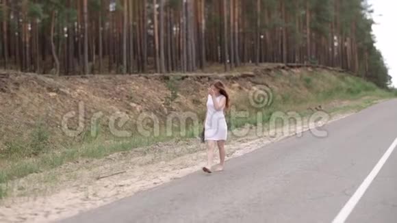快乐的女孩穿着一件白色的连衣裙手里拿着一束花赤脚在路上行走视频的预览图