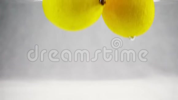 亮黄色柠檬落入水中气泡较大动作缓慢孤立白色背景上的水果视频的预览图