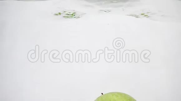 绿色的苹果缓慢地漂浮在一个水的容器里视频的预览图