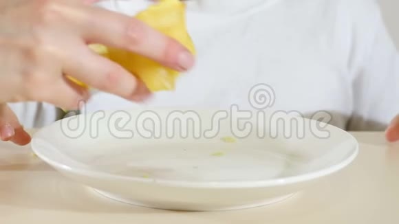 一个孩子正在吃薯片坐在一张白色背景的桌子上特写视频的预览图
