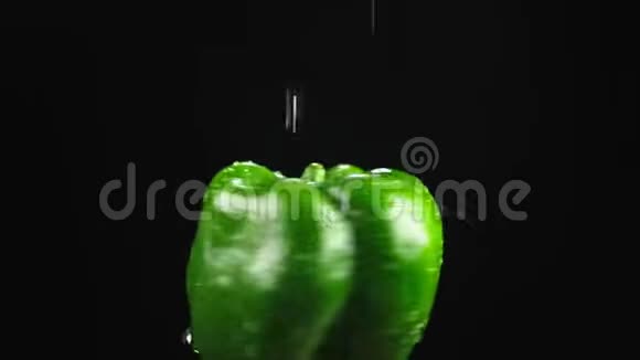 青椒特写水滴落在黑色背景上旋转的苹果上超级慢动作视频的预览图