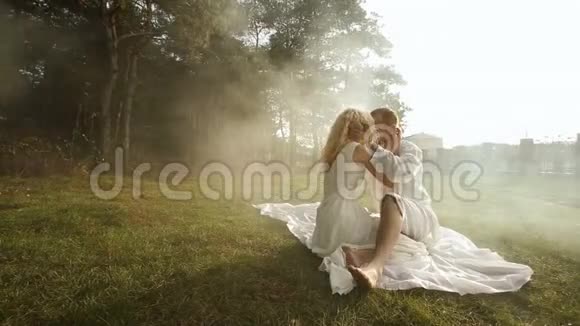 在秋天公园的草地上一对穿着白色衣服的快乐情侣正在接吻视频的预览图